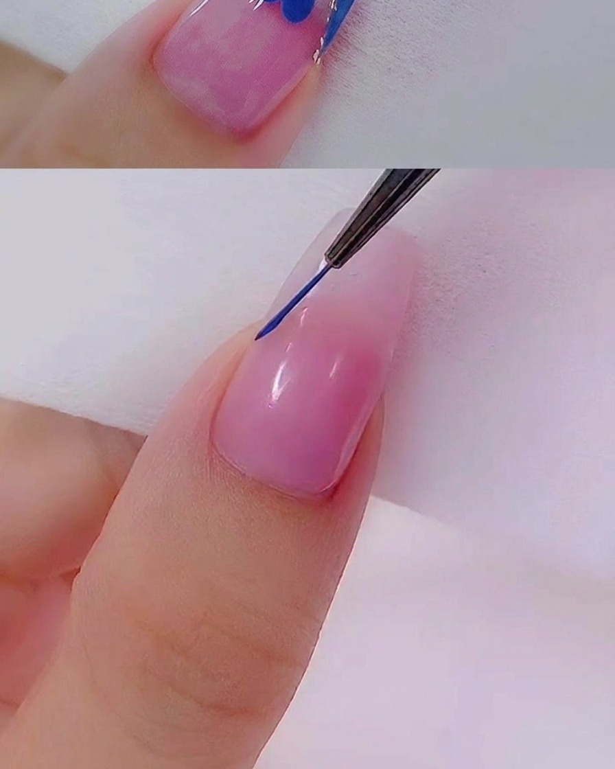 A close-up view of a fine liner brush creating a precise blue line across the tip of a natural-looking nail.