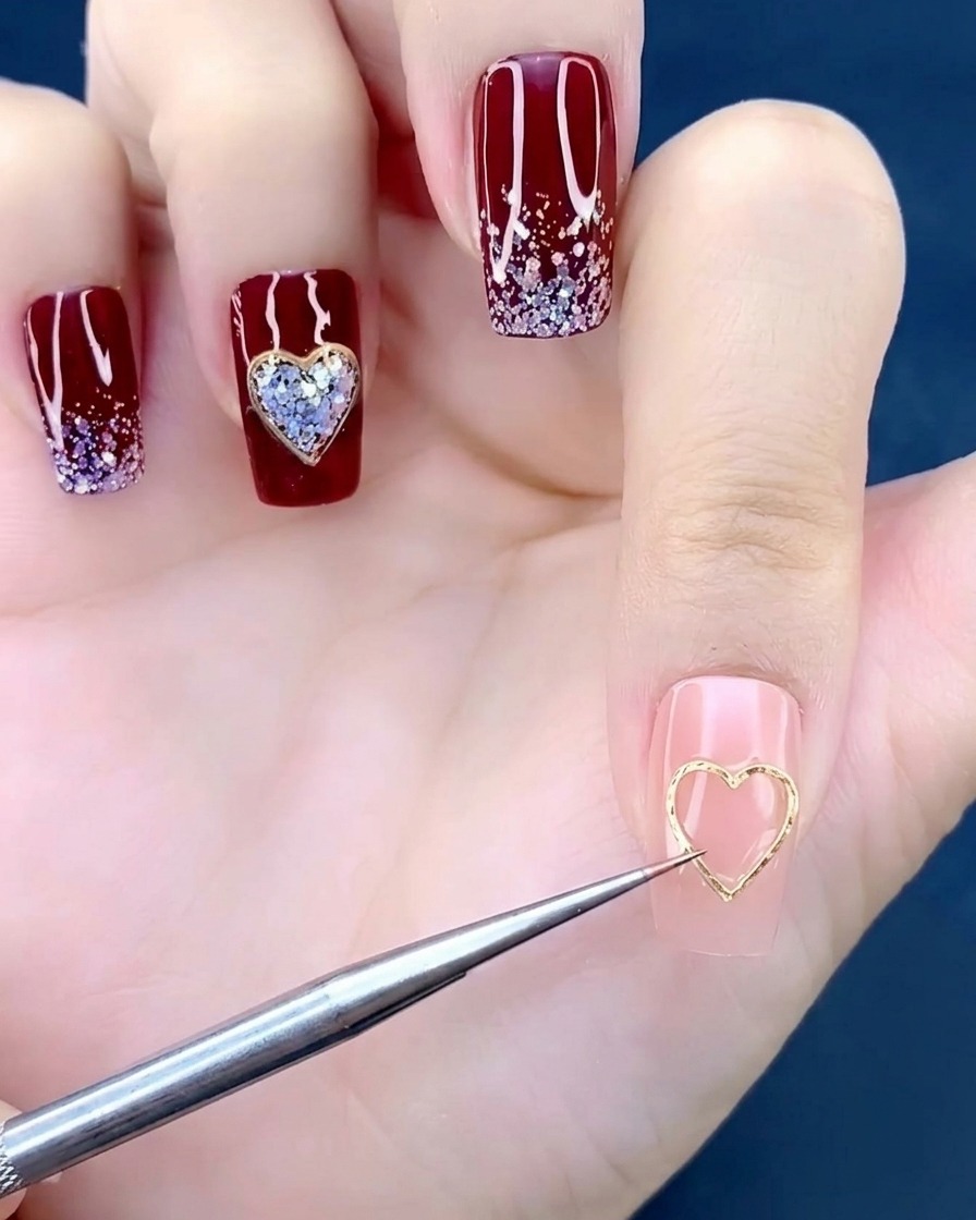 A close-up of a nail brush applying a small drop of clear adhesive gel to the center of a manicured nail.