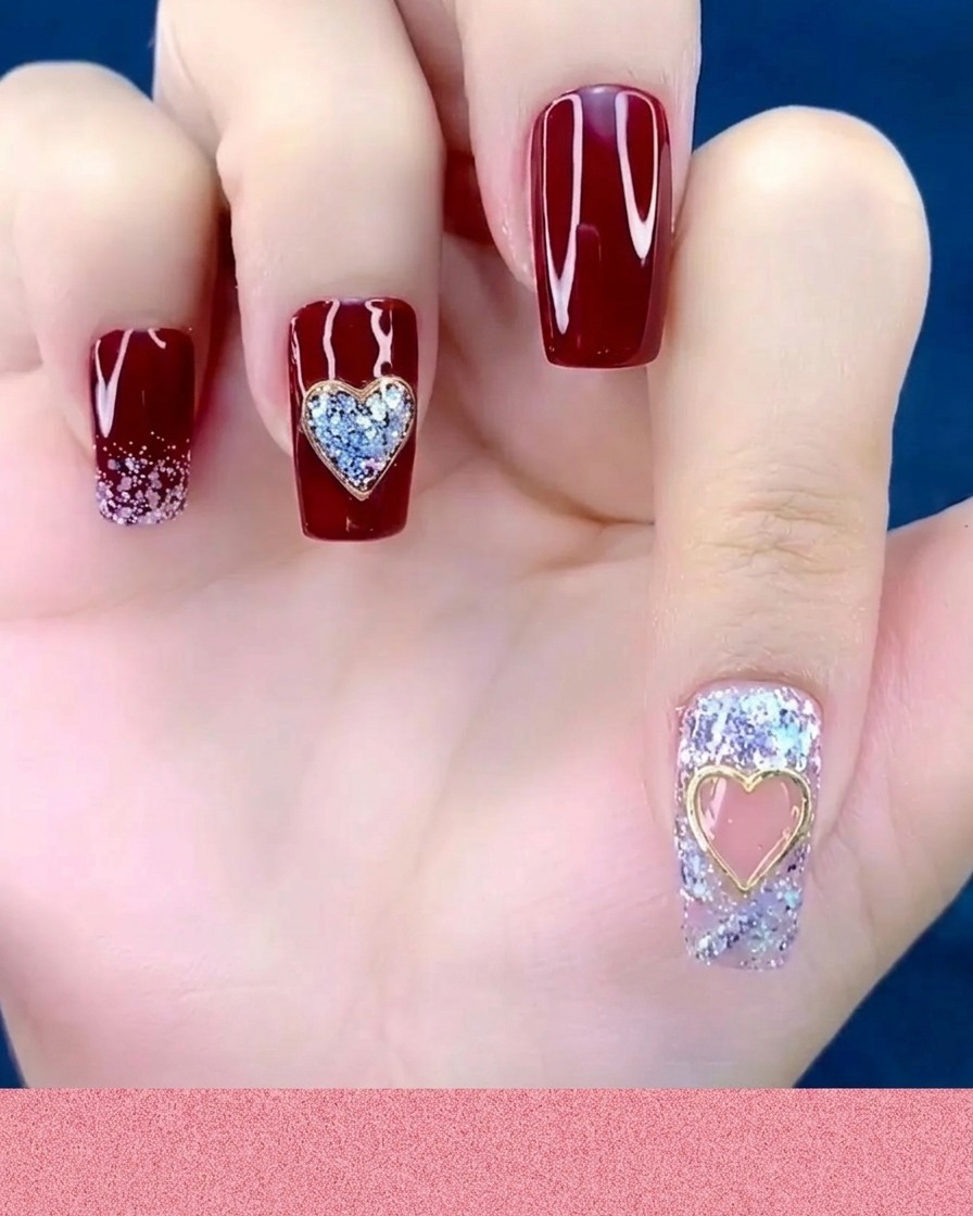 A cuticle pusher or silicone tool pressing down on a metal heart charm already placed on a fingernail.