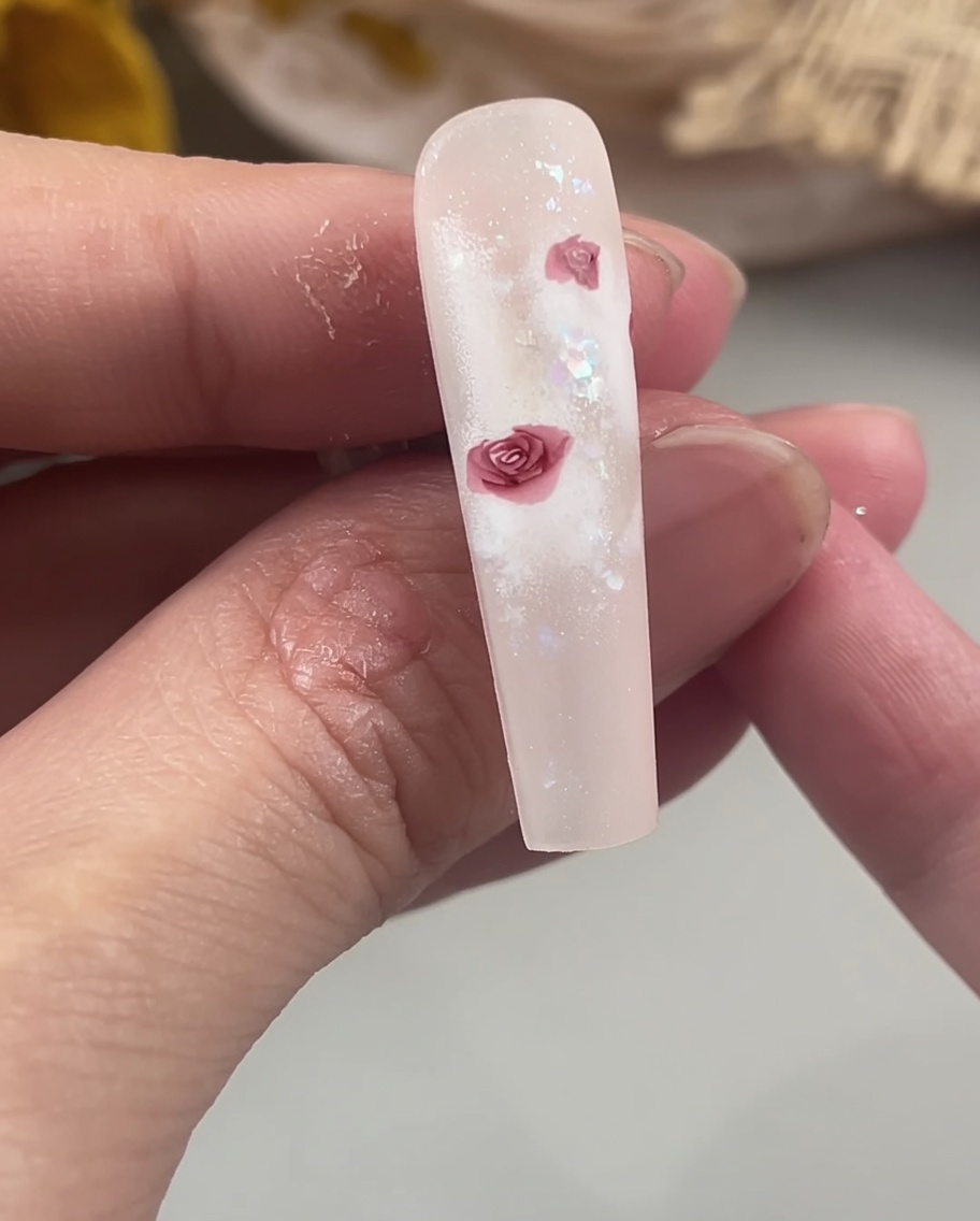 A detail brush filling in the centers of rose petals on a nail to create a solid, defined floral shape.