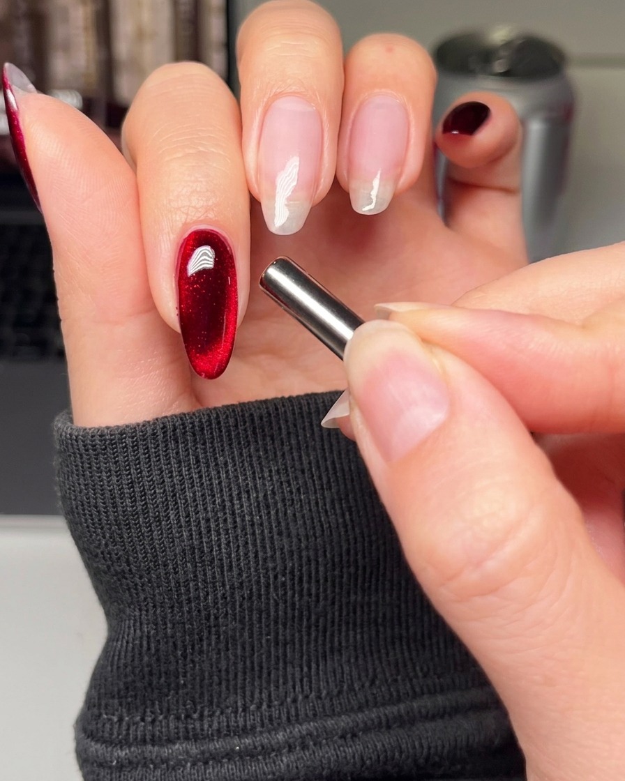A nail brush applying a smooth coat of black gel polish to the index fingernail.