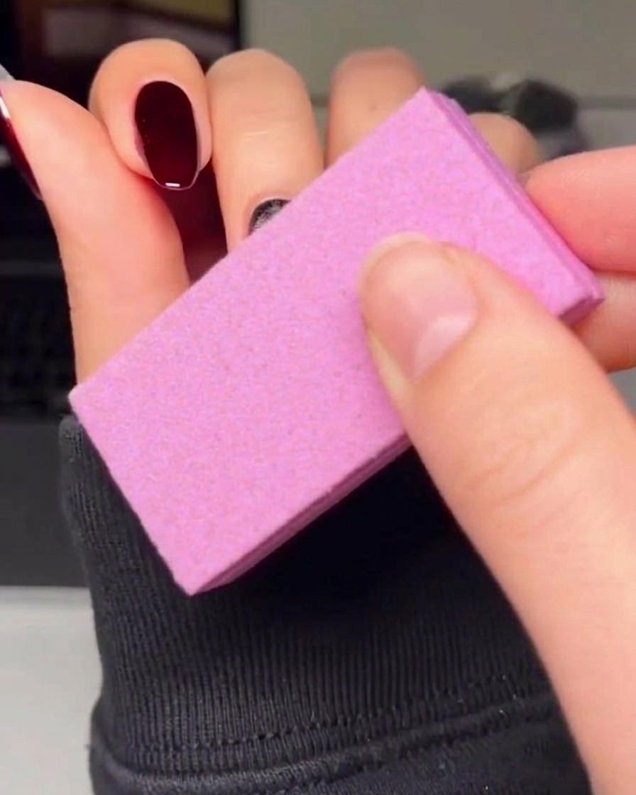 A thin liner brush carefully outlining a red heart shape on a nail with black gel polish.