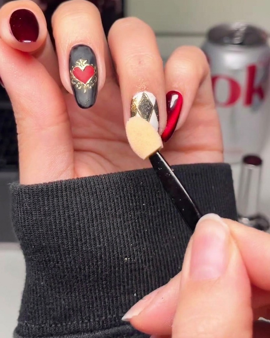 A close-up of an argyle-patterned nail receiving small gold accents at the line intersections.