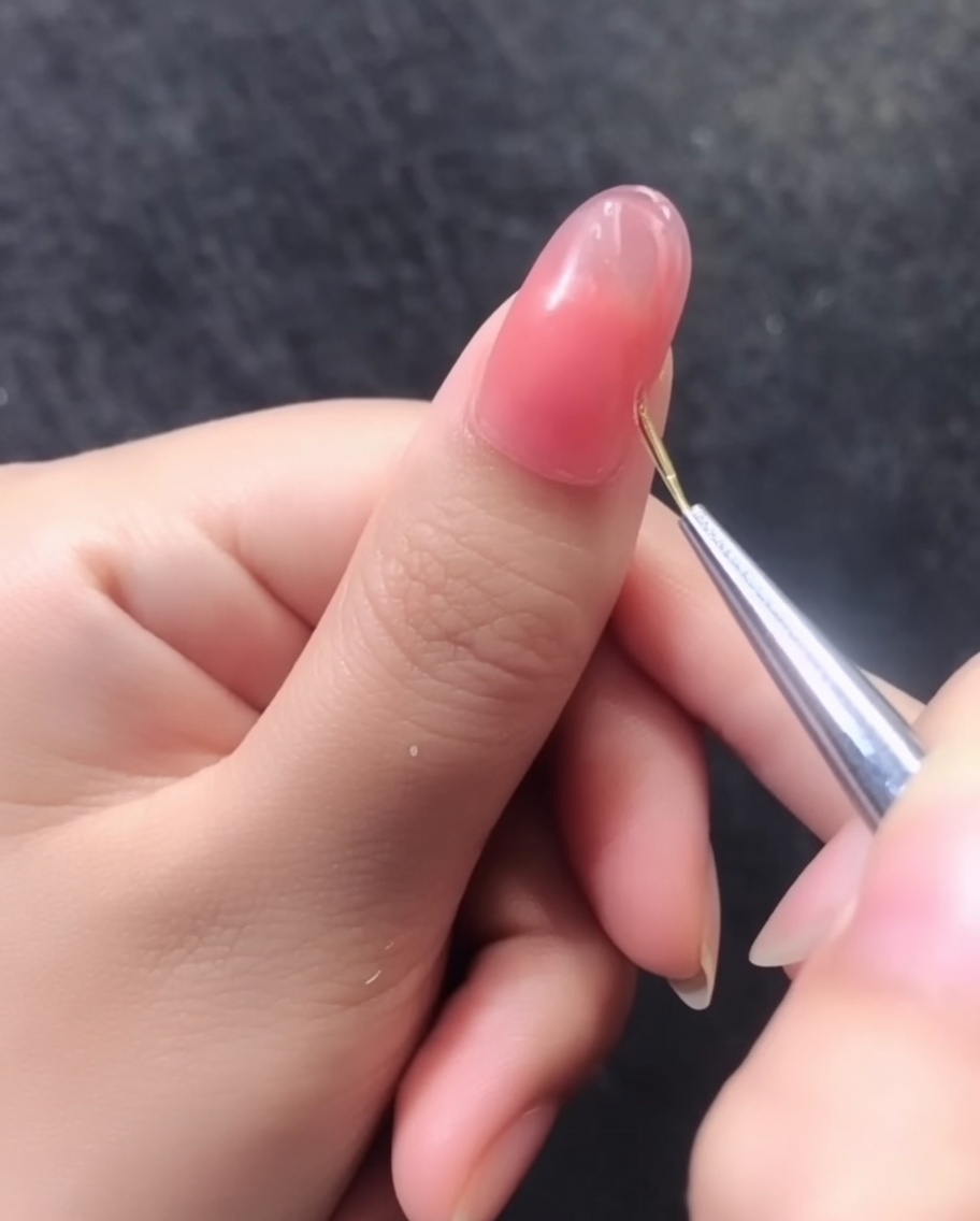 A detailed view of a completed 3D gold line pattern on a pink gel nail.