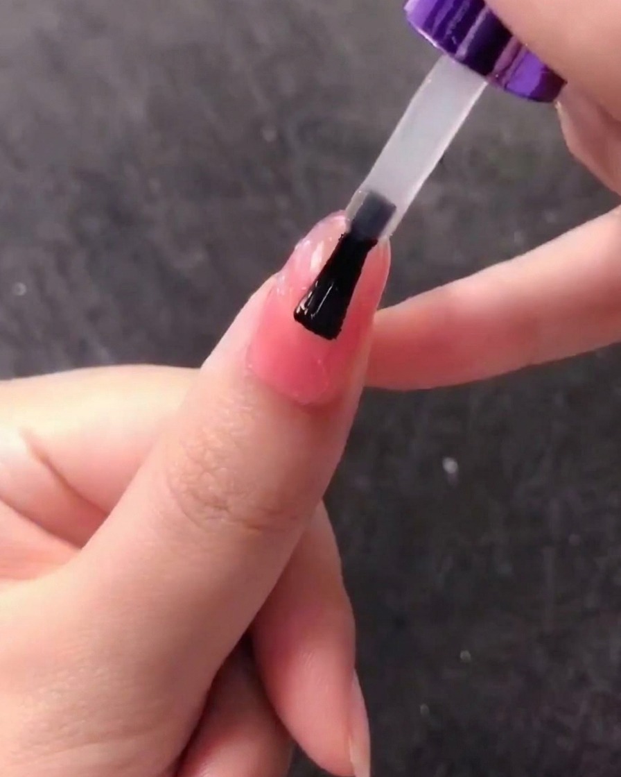 A brush applying a layer of clear gel over the textured seashell nail design.