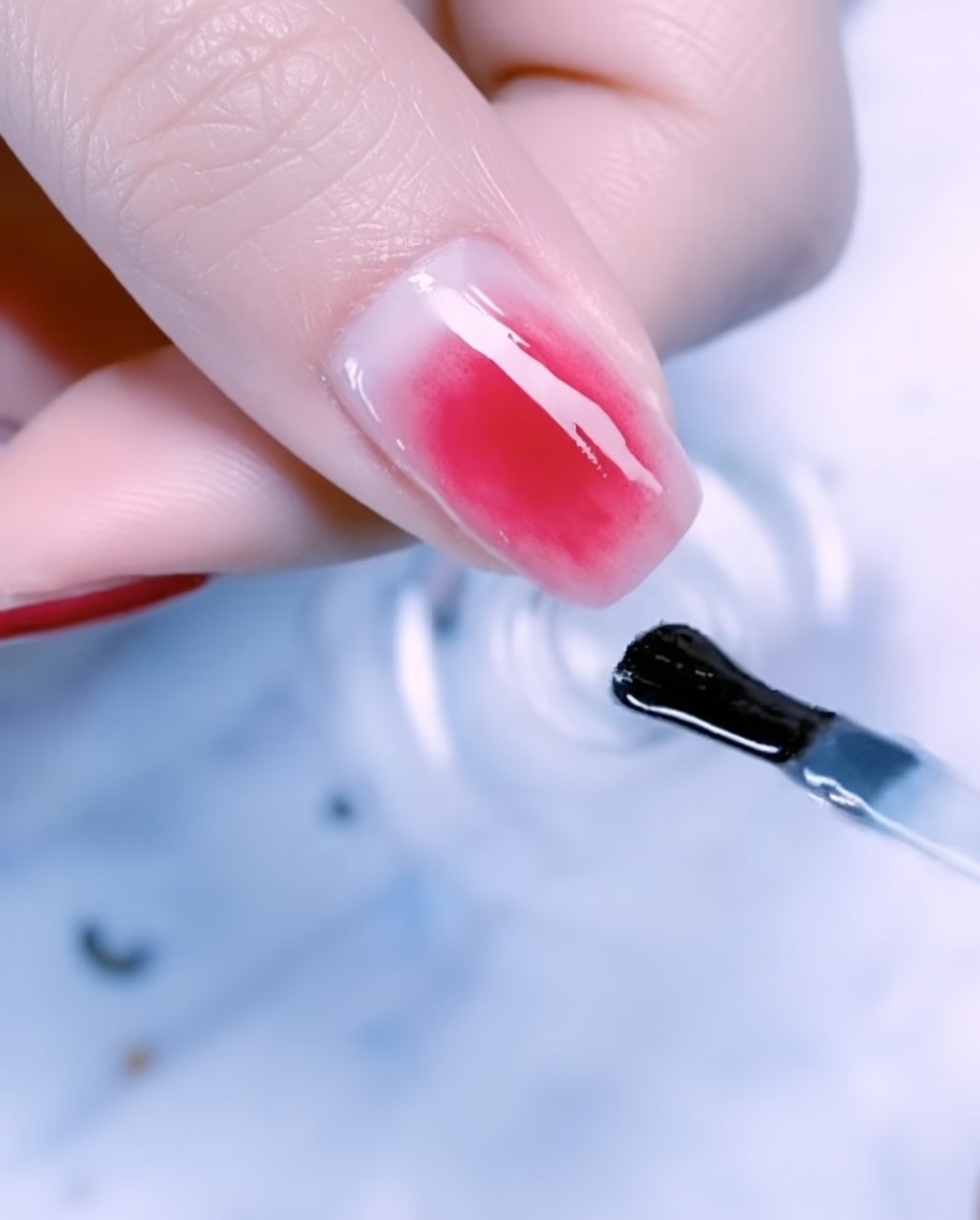 A close-up of a thumbnail decorated with gold foil, thin metal wire accents, and pearls over a rose gold gradient.