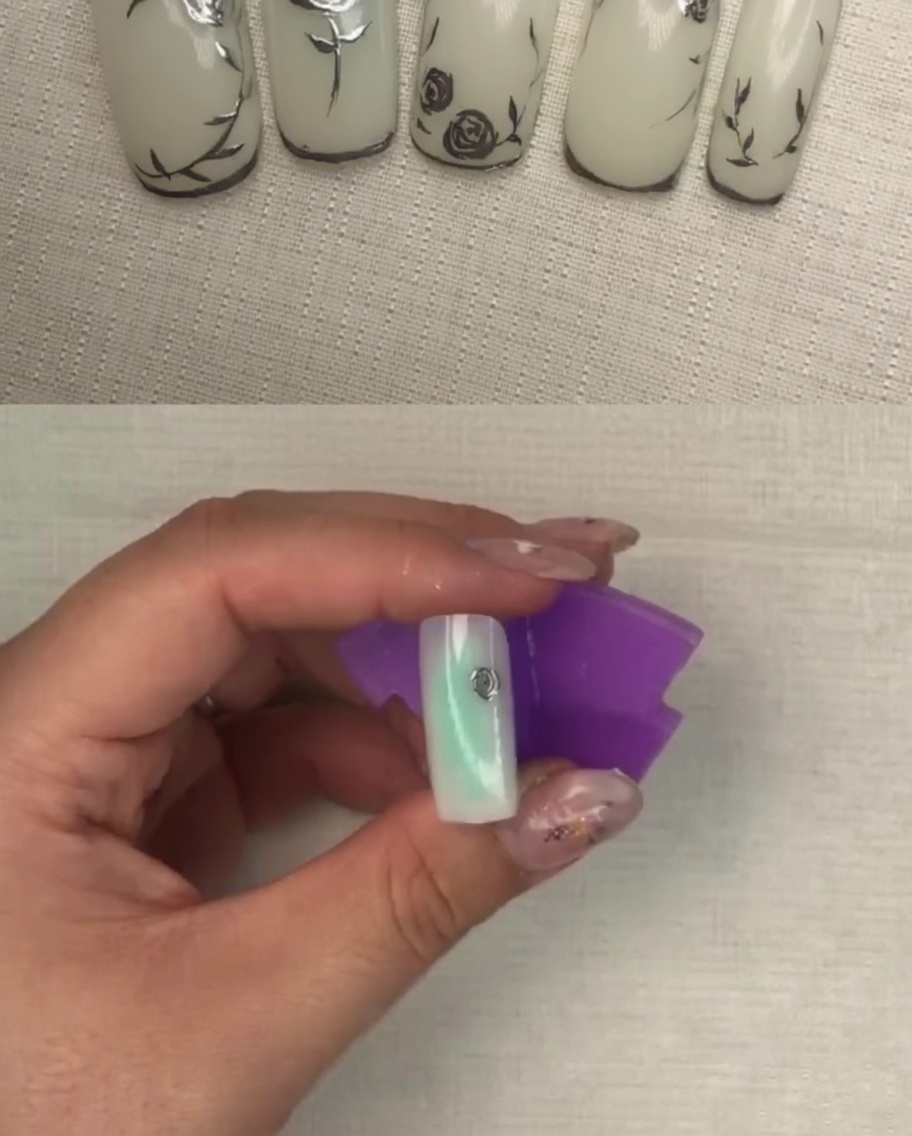 A nail with a more defined metallic flower design featuring multiple petal layers.