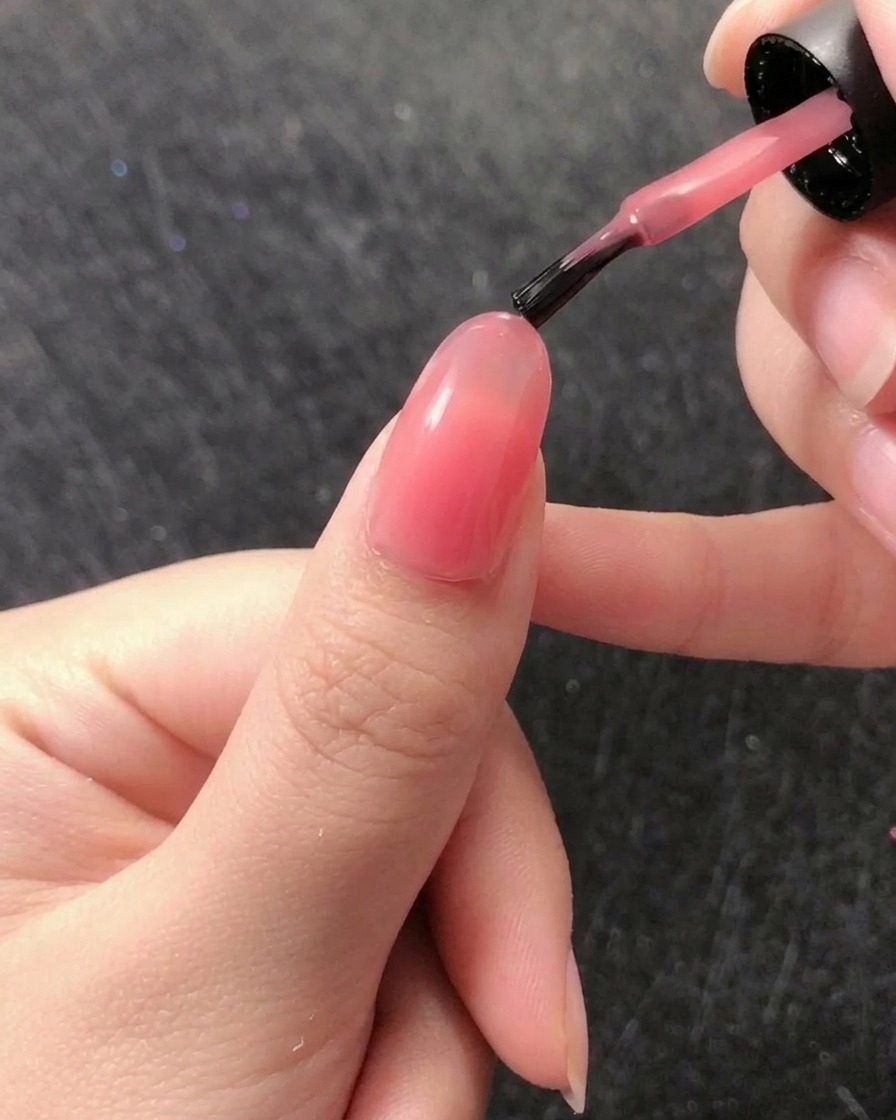 A thin liner brush lifting a small bead of clear builder gel from the jar.