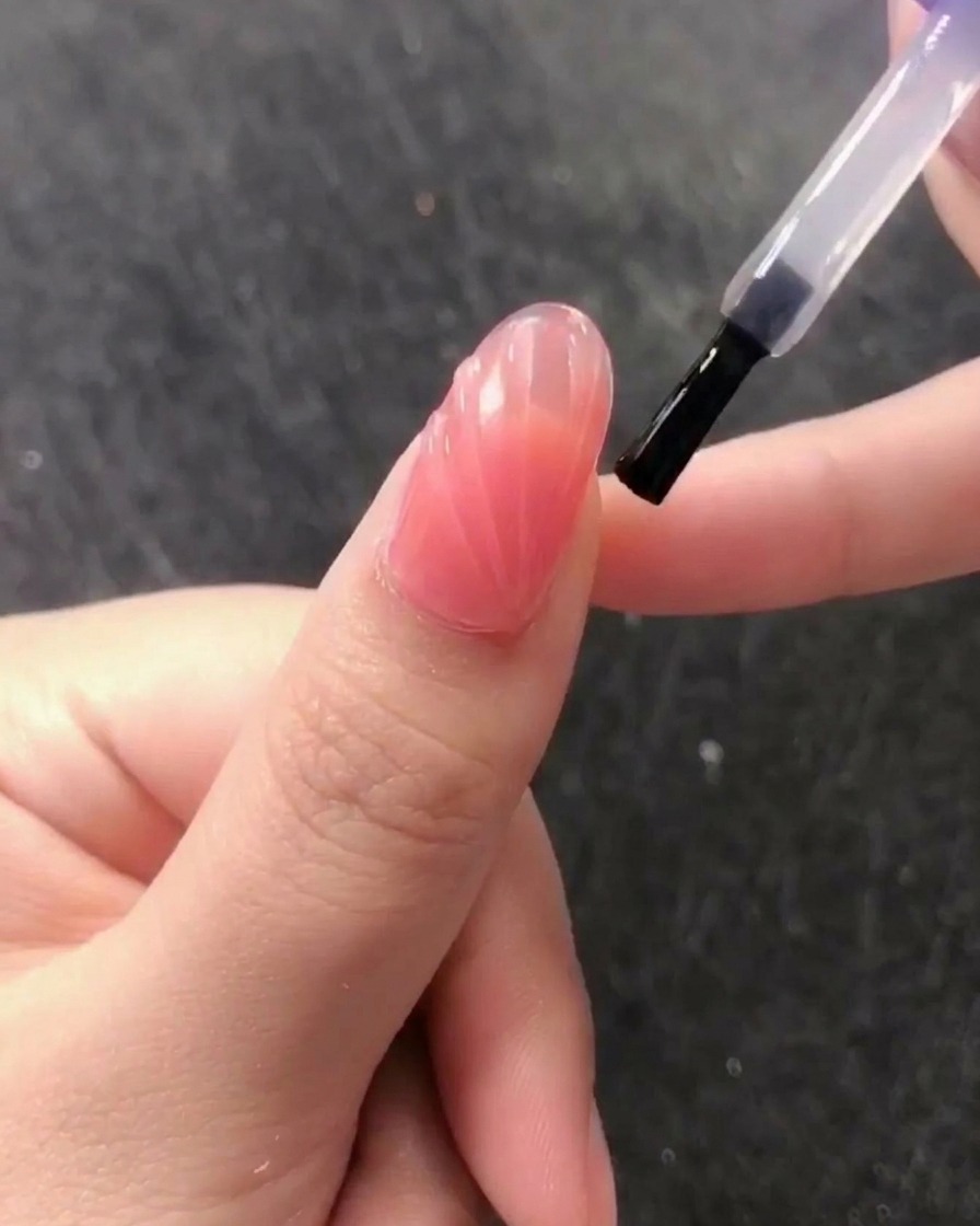 A brush applying a clear, glossy no-wipe top coat over the textured shell design.