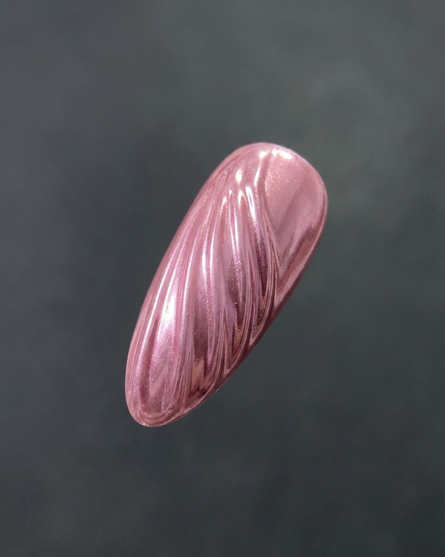 A brush applying a clear, glossy top coat over a textured, chrome-finished nail.