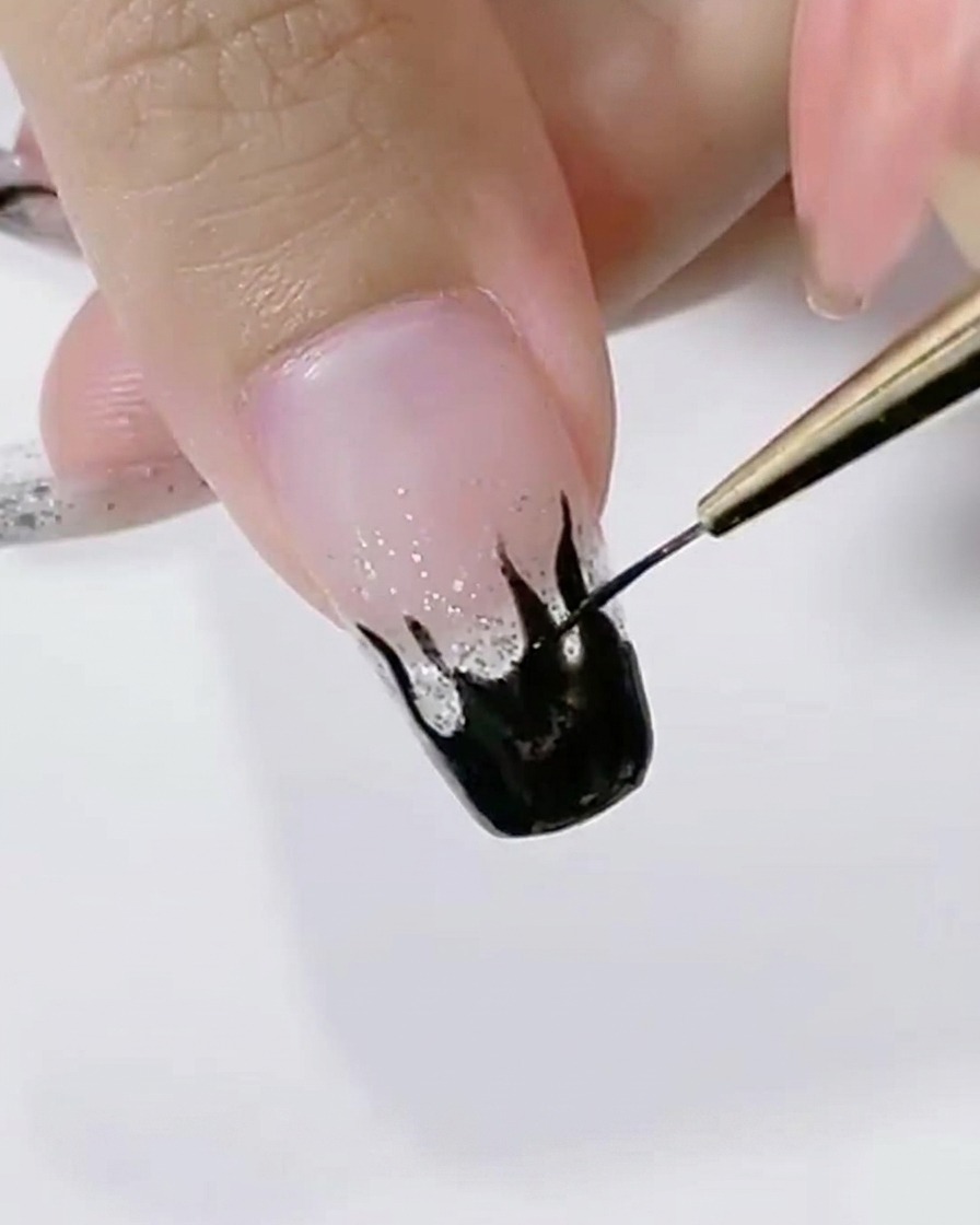 A detail shot showing a liner brush smoothing the edge of a black flame design.