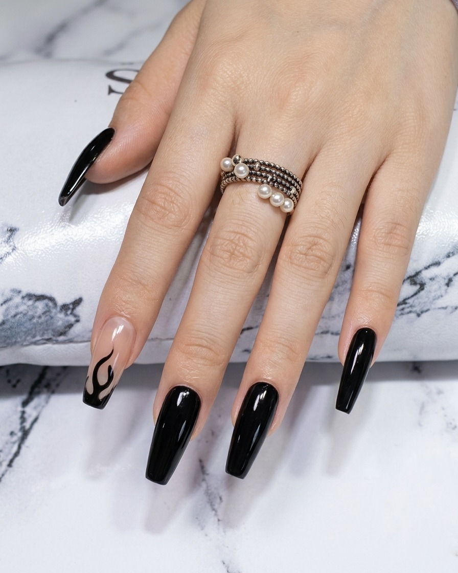 A close-up of a liner brush sharpening the edges and points of a black flame design on a chrome nail.