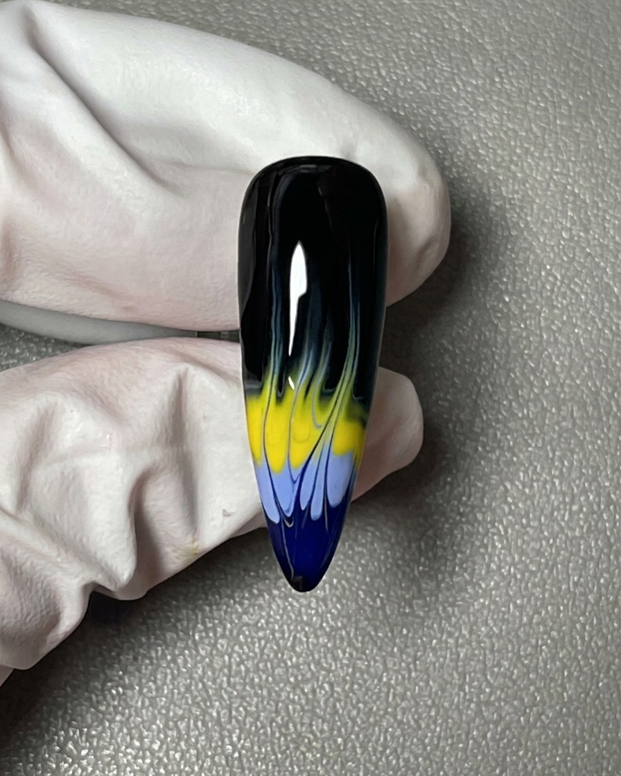 A close-up of a nail fully coated in a smooth, opaque black gel polish.