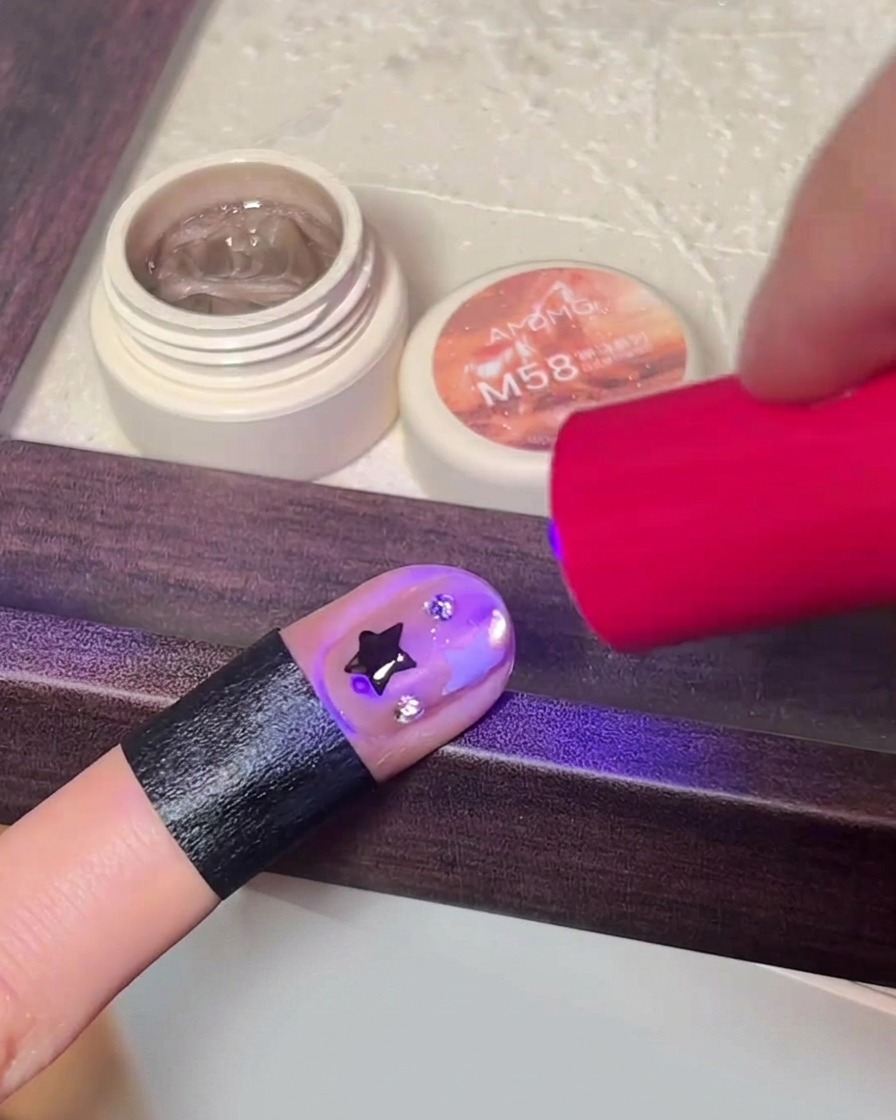 A hand curing the final nail design inside a portable LED nail lamp.