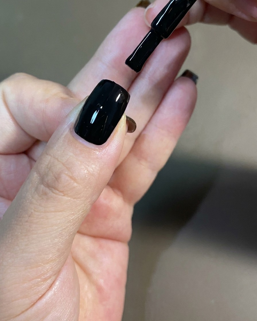 A hand positioned inside a professional UV nail lamp for curing.