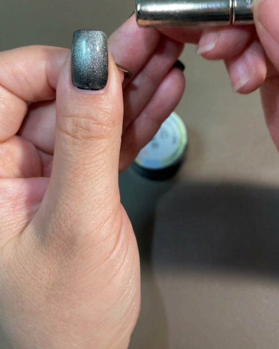 A bar magnet held near the side of a fingernail to influence the cat-eye pigment.
