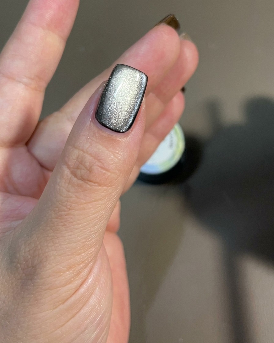A magnet being moved along the nail surface to direct the shimmering magnetic particles.