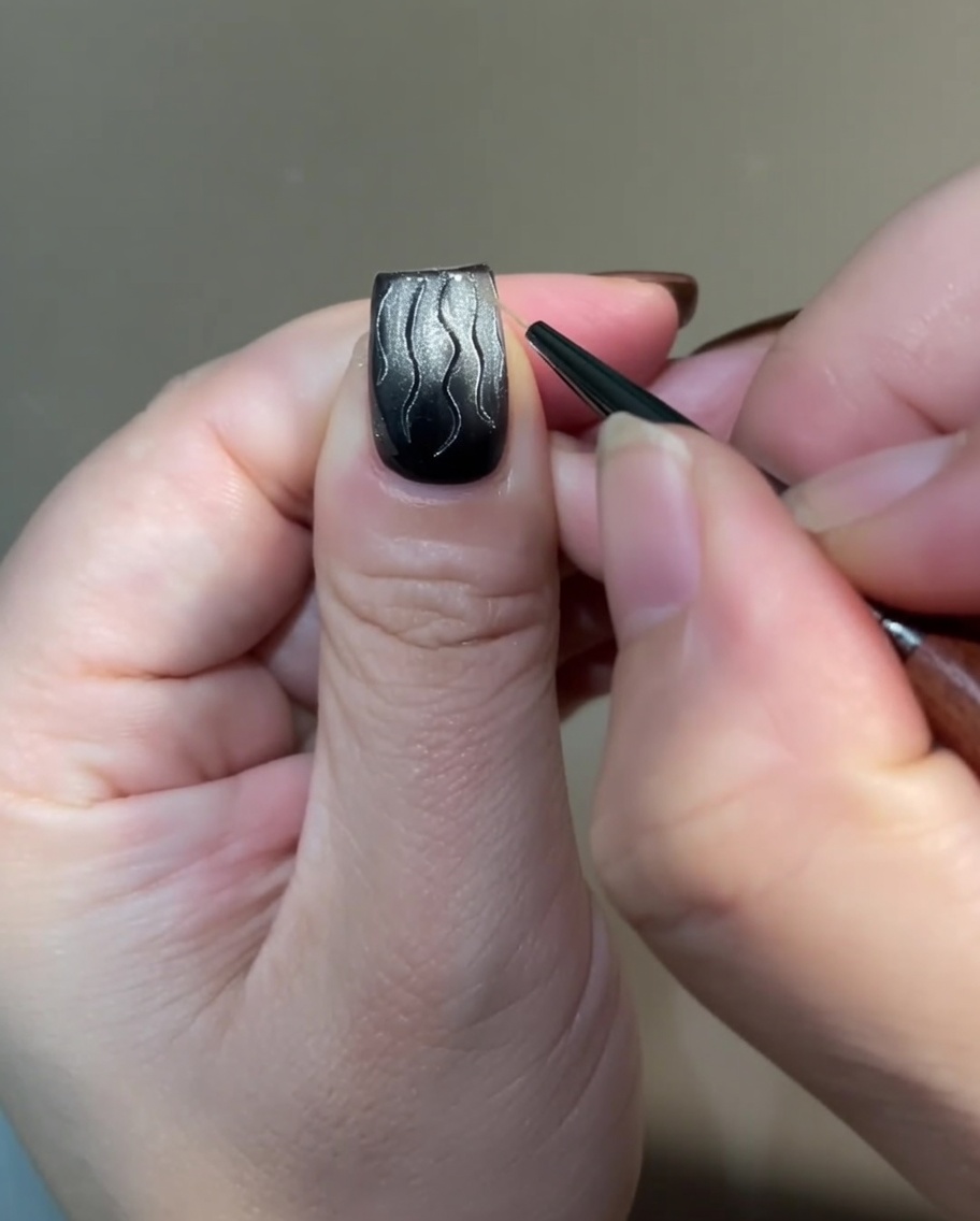 A detailed view showing the base of the flame art being connected with thin, cross-hatched lines using a liner brush.