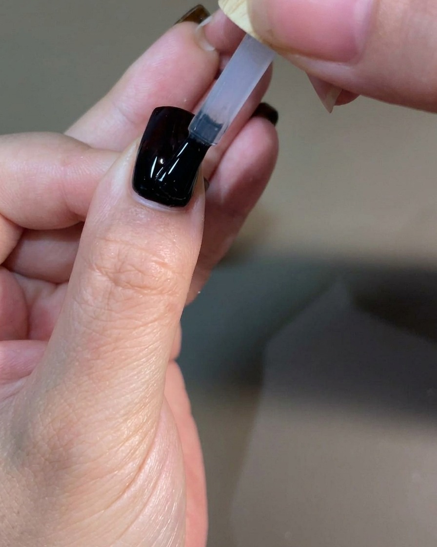 A manicured hand curing the final top coat layer inside a professional UV nail lamp.