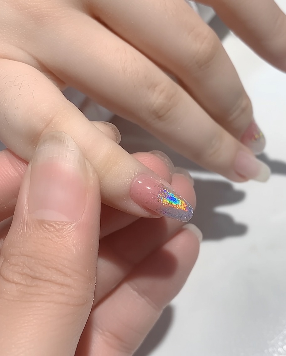 A hand positioned inside a UV nail lamp to cure the freshly applied powder.