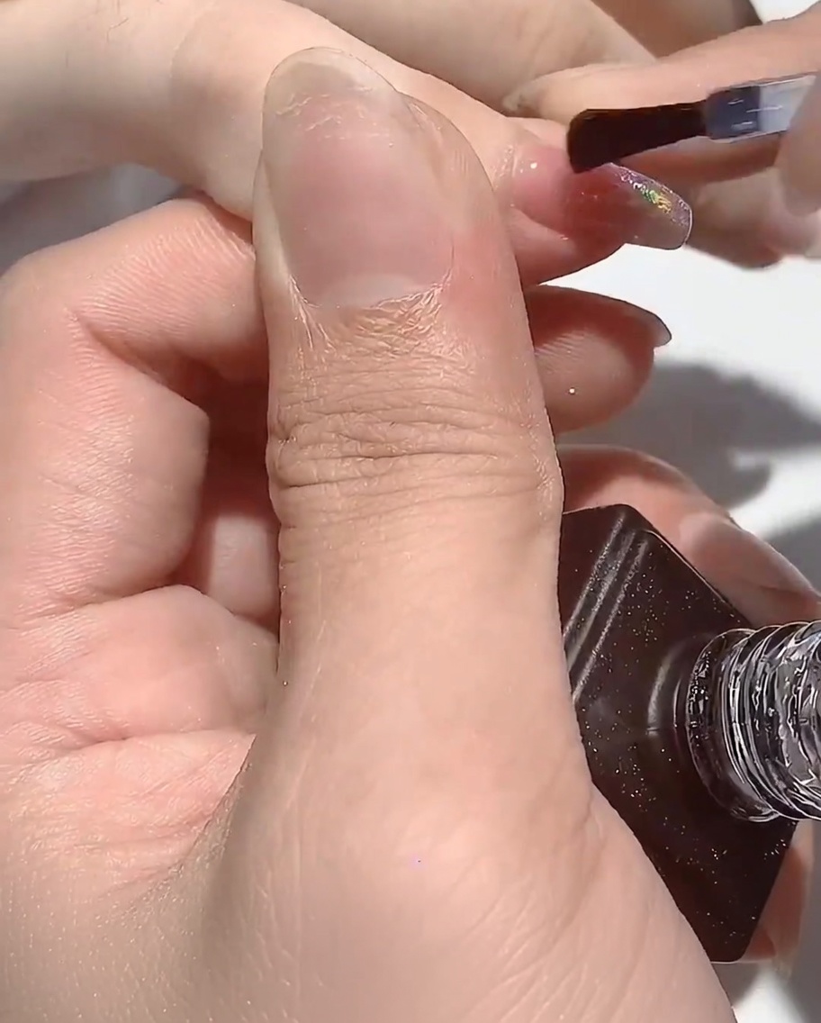 The hand resting under the UV lamp, with the nails curing.