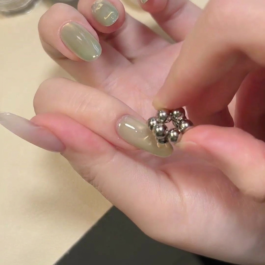 A small tool featuring a cluster of spherical magnets held over the center of a nail.