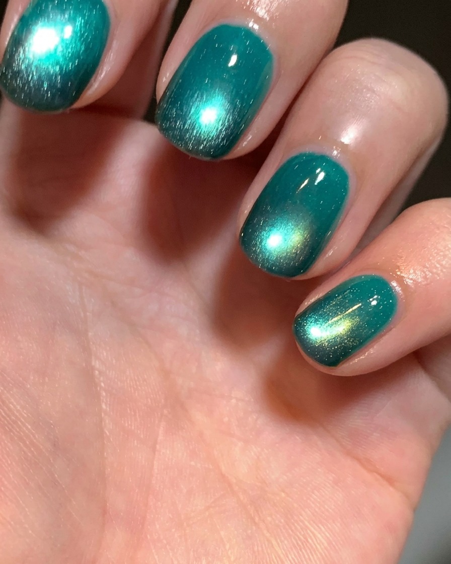 A close-up of a finger tip where black gel is being applied to the natural nail using a small cosmetic sponge.