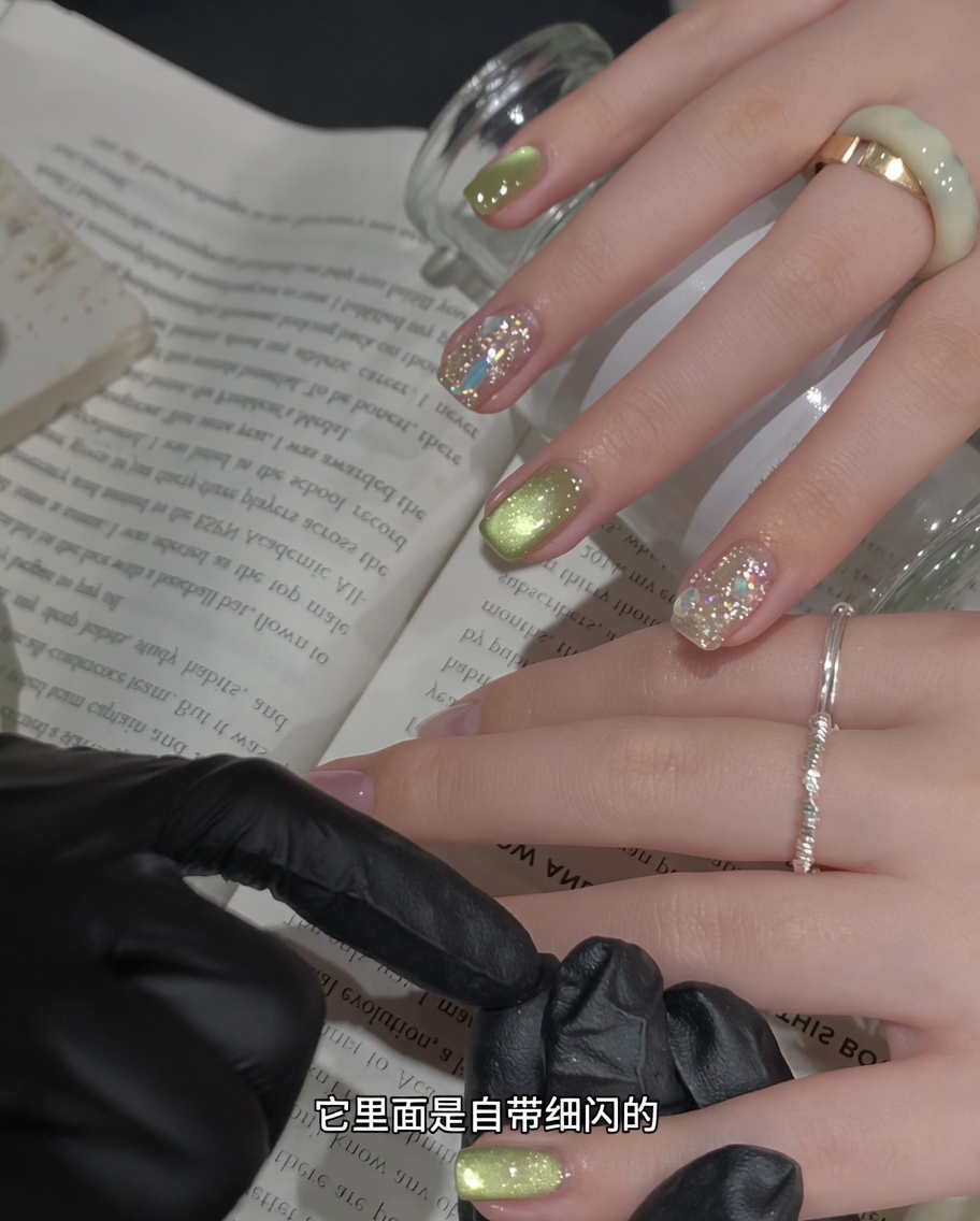A magnetic nail tool held close to a wet, shimmering green gel-painted nail to manipulate the magnetic particles.