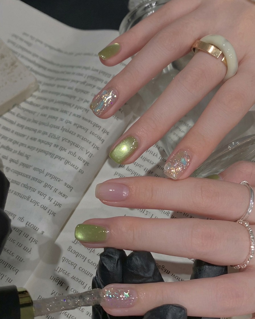 A brush applying a coat of dense, sparkling silver glitter gel polish to an accent fingernail.