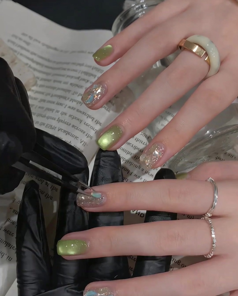 A brush applying a clear, glossy top coat over an accent nail decorated with rhinestones.
