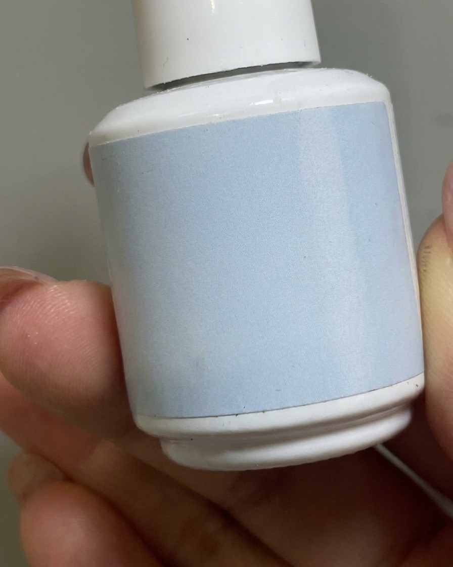 A brush applying a clear matte top coat over the nude gel base on a nail.