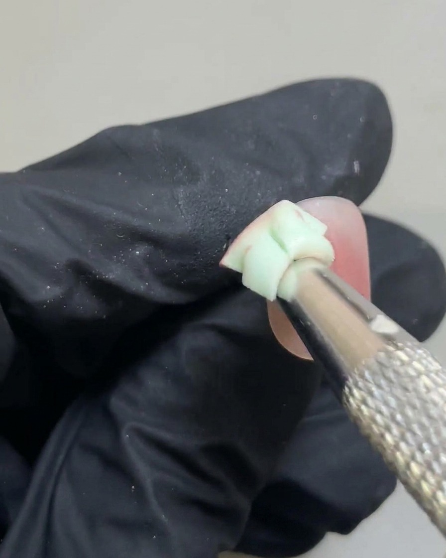 A small sponge gently blending the edges of a pink gel spot to create a soft blush gradient.