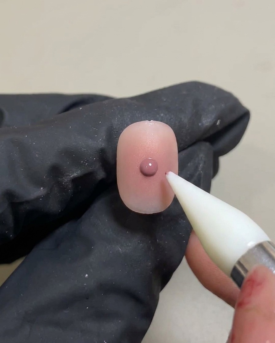 A silicone tool applying a small, concentrated dot of pink gel over a previously cured blush gradient.