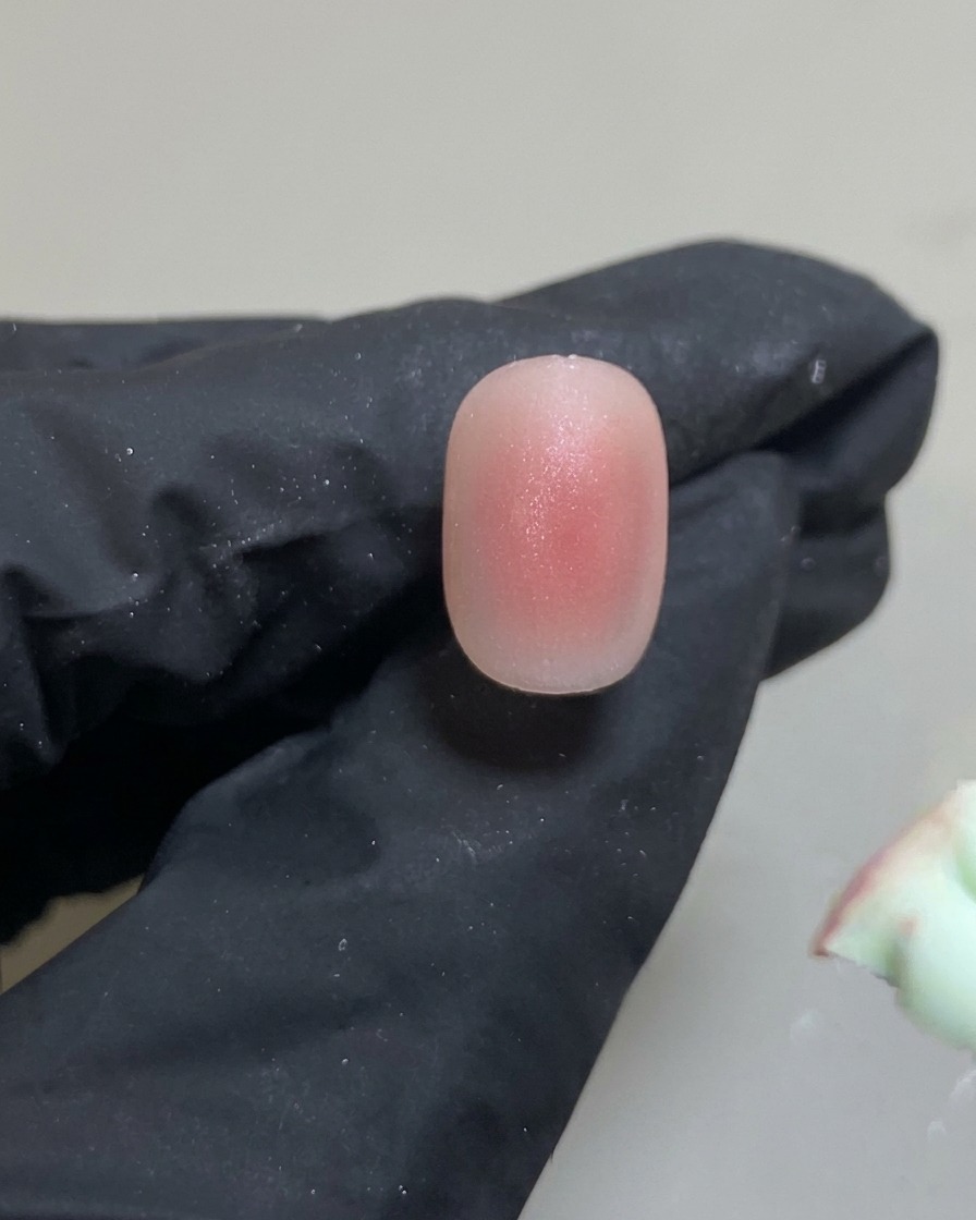 A silicone tool placing a small, precise dot of pink gel in the center of the nail.