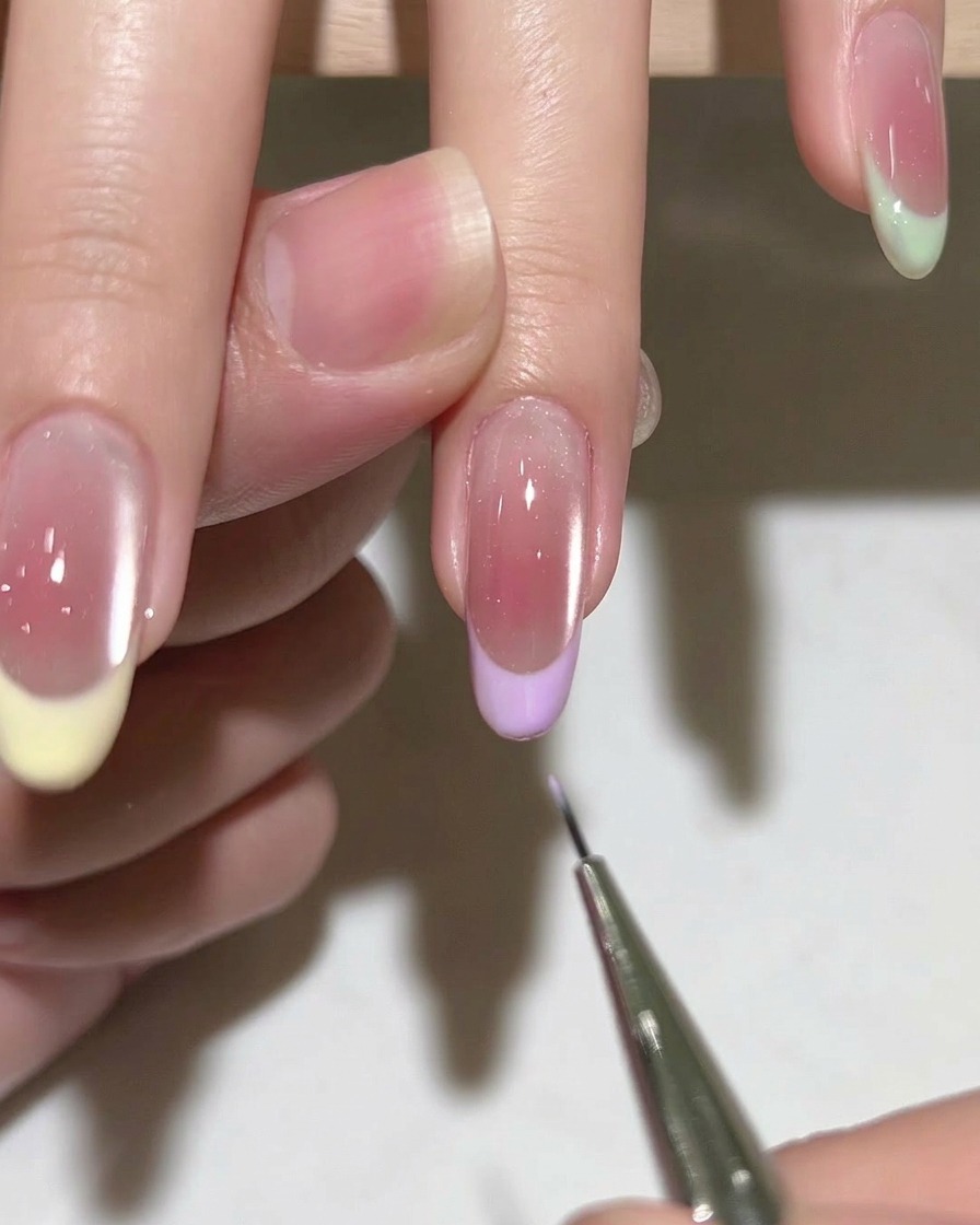 A close-up of a nail brush applying clear gel base coat to a clean, prepped natural nail.
