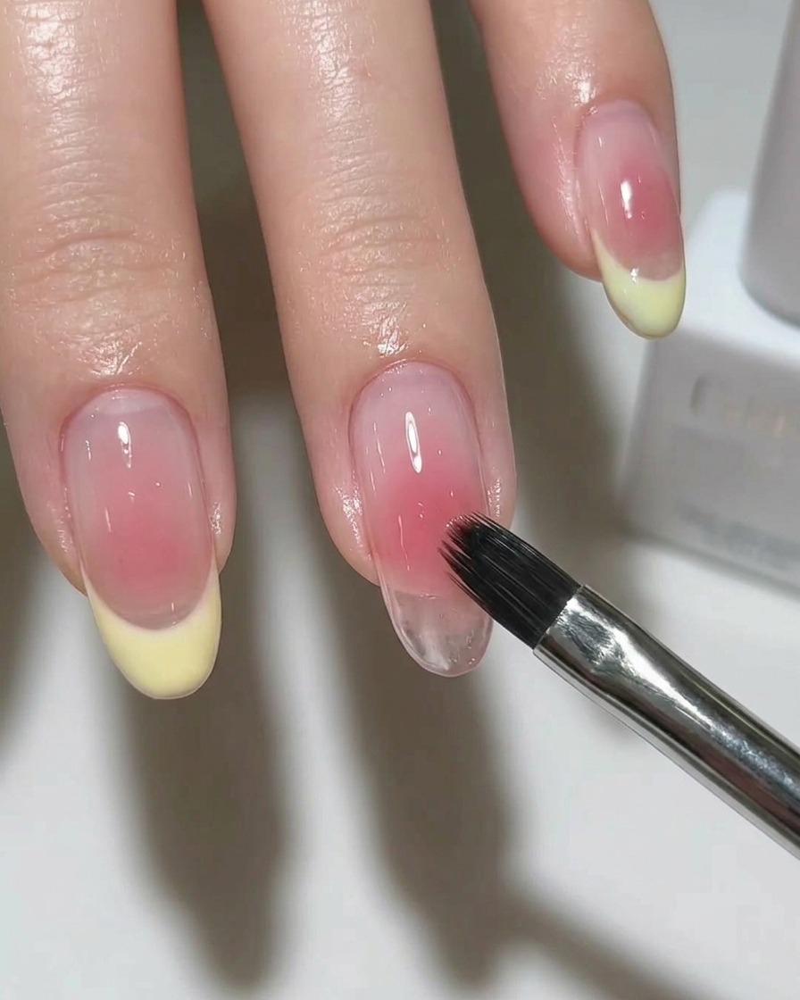 A brush applying a shimmering silver magnetic polish over a nail base.