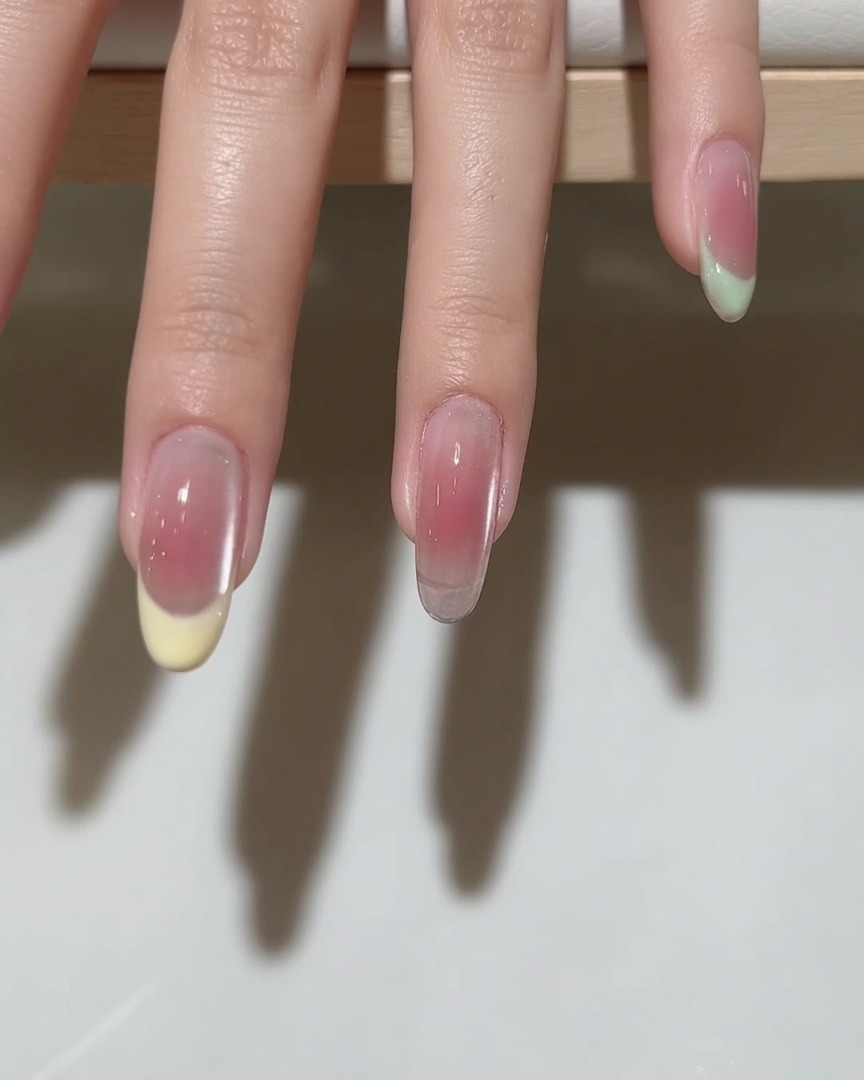 A fine-liner brush drawing a precise smile line on a nail to prepare for a French tip design.