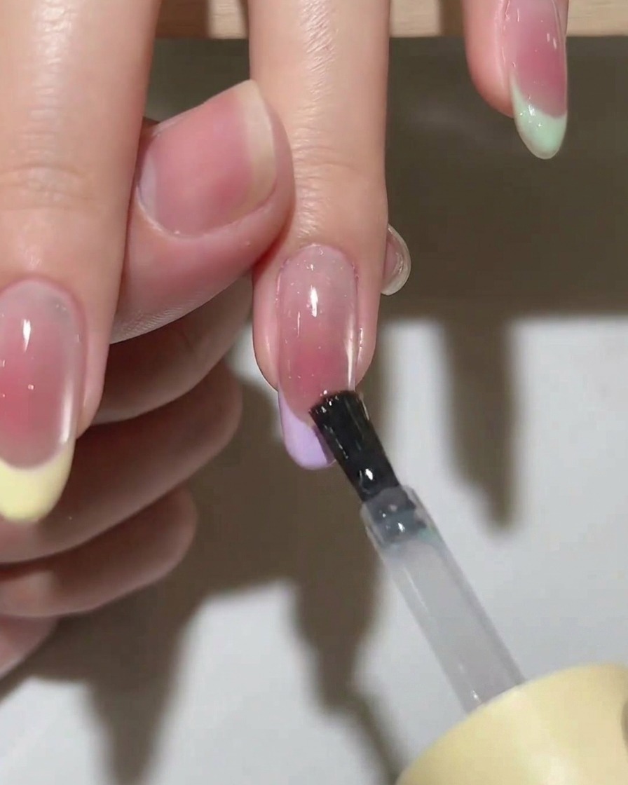 A hand placed inside a UV/LED gel nail lamp with the light turned on for curing.
