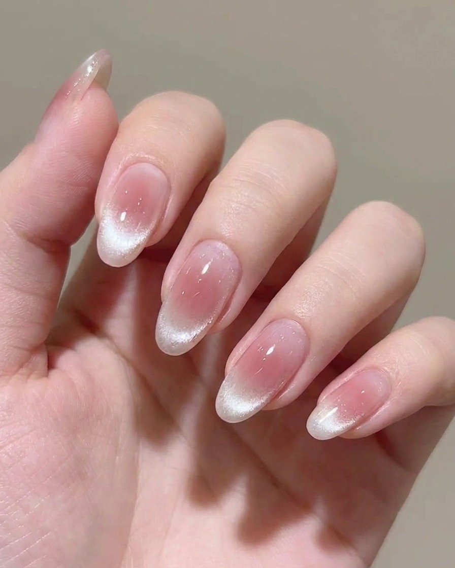 Applying a second coat of sheer pink gel polish to the nail.
