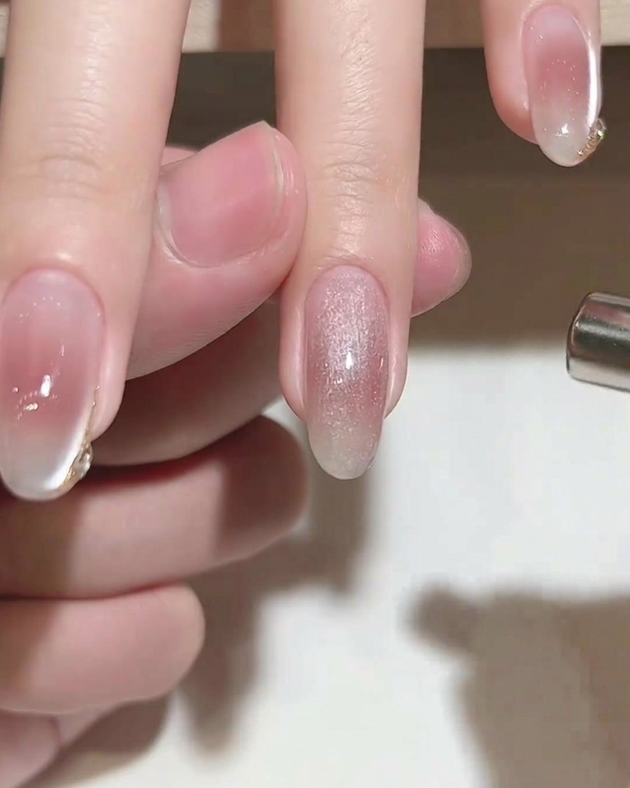 A cylindrical magnet being held over a nail coated with wet cat-eye gel to create a shimmer effect.