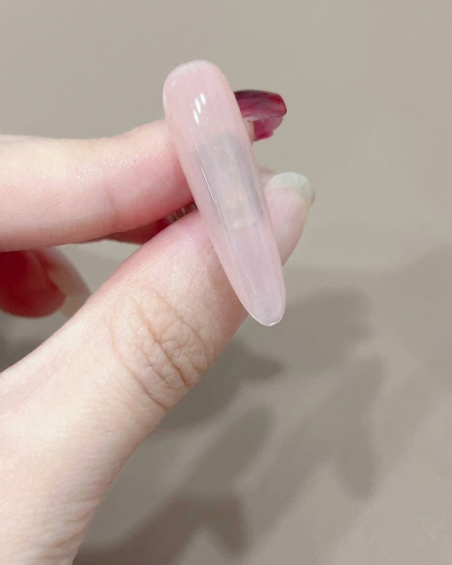 A single nail being cured under a small, handheld portable UV lamp.