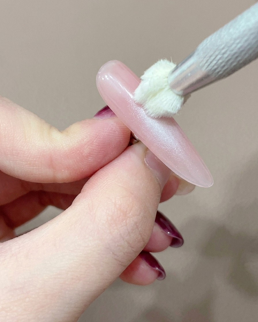 A silicone applicator tool carefully adding a concentrated dot of pink gel to the center of the nail.