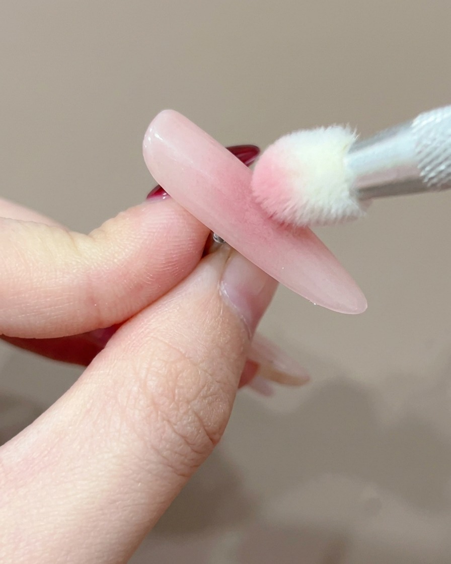 A close-up of a nail tip positioned under a UV lamp for curing.
