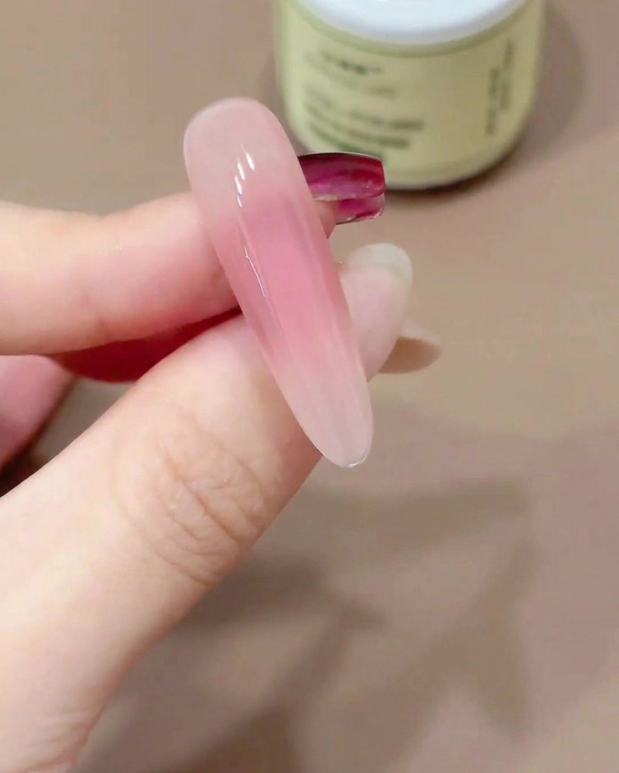 A nail tip held upside down to allow the gel top coat to self-level.