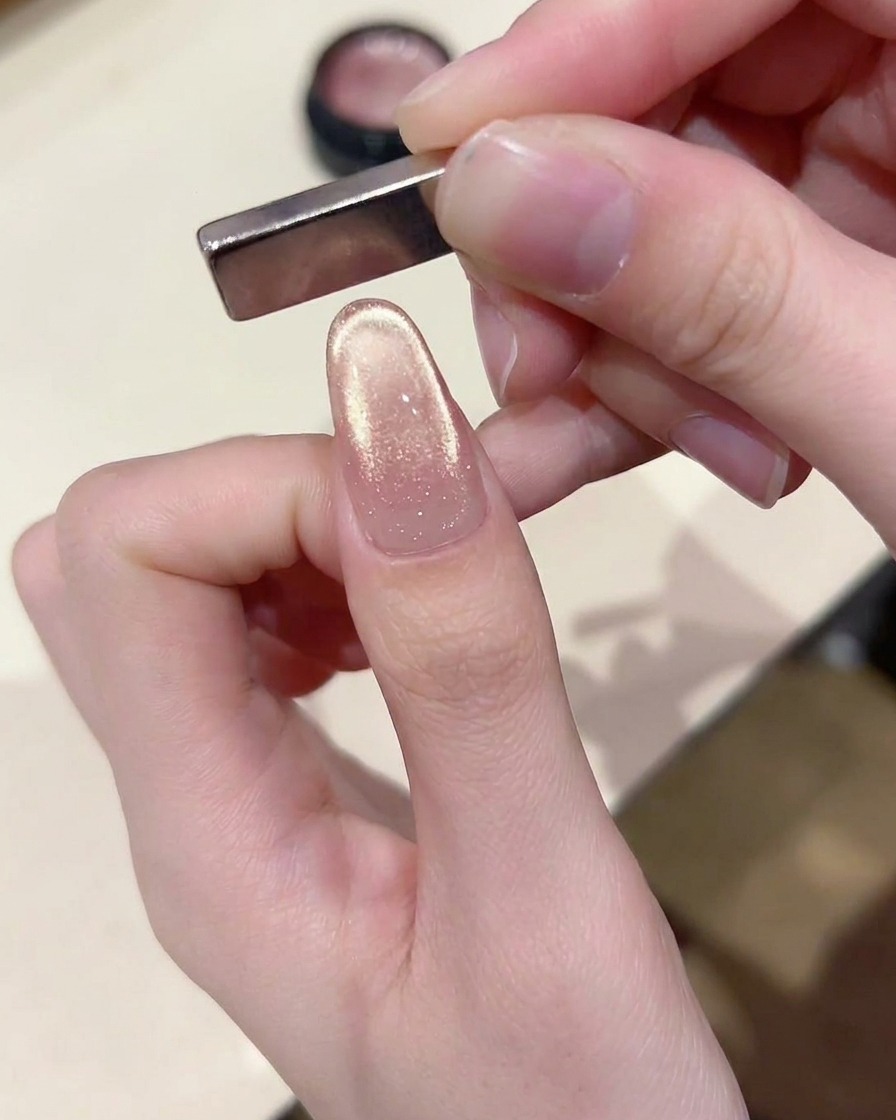 A magnetic tool angled over the nail tip, creating a distinct French-style curved line of light.