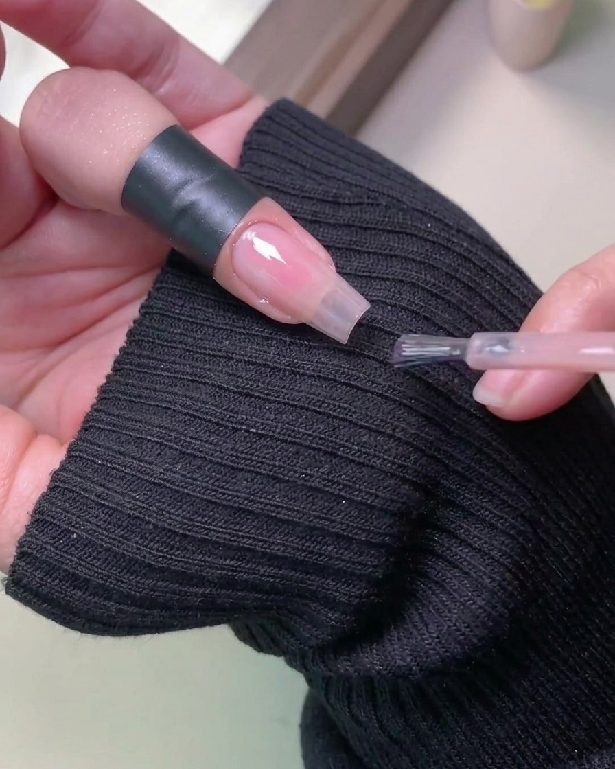 A hand placed inside a professional UV nail lamp for curing the gel polish.