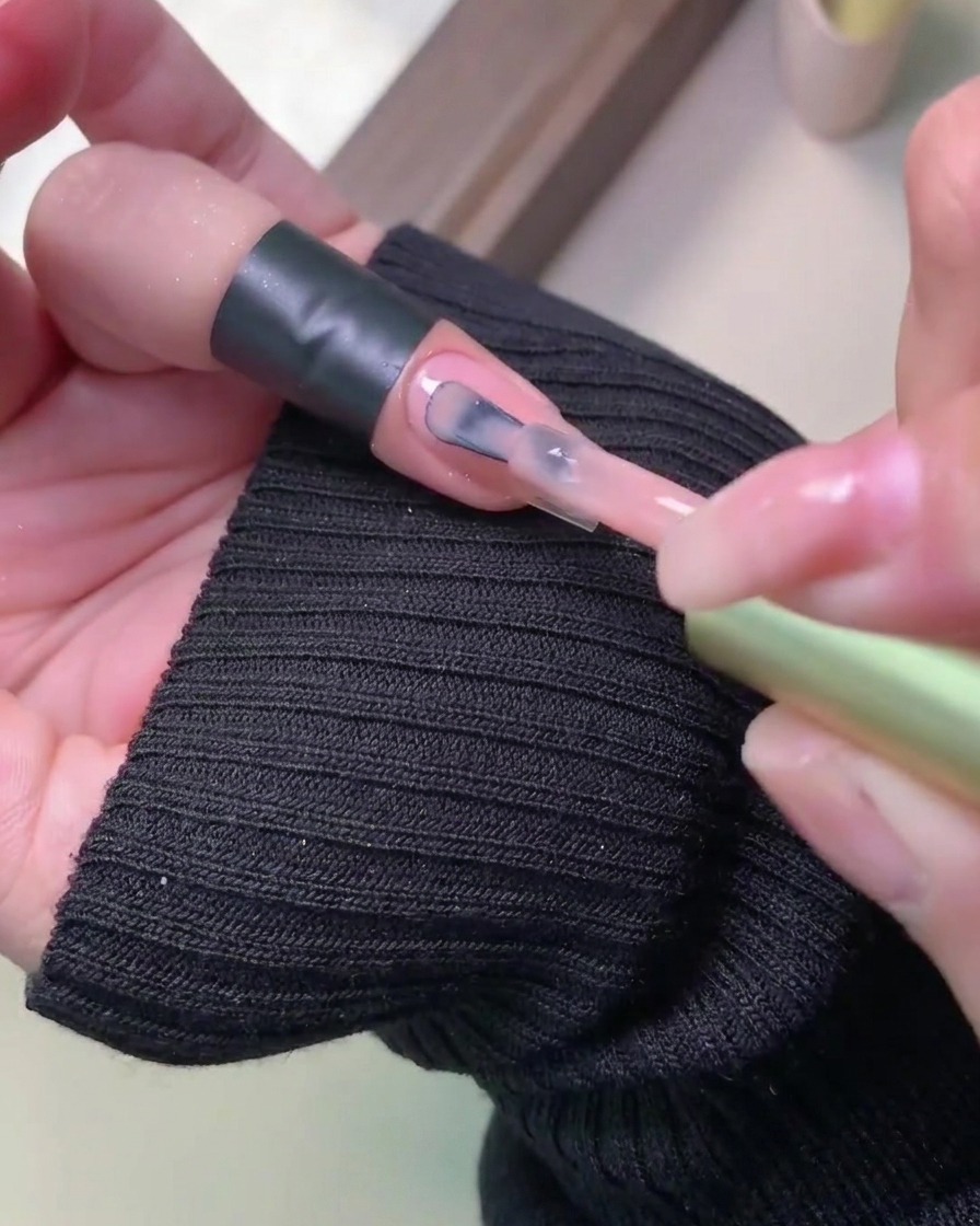 A close-up showing a second coat of colored gel polish being applied smoothly over the previously cured layer.