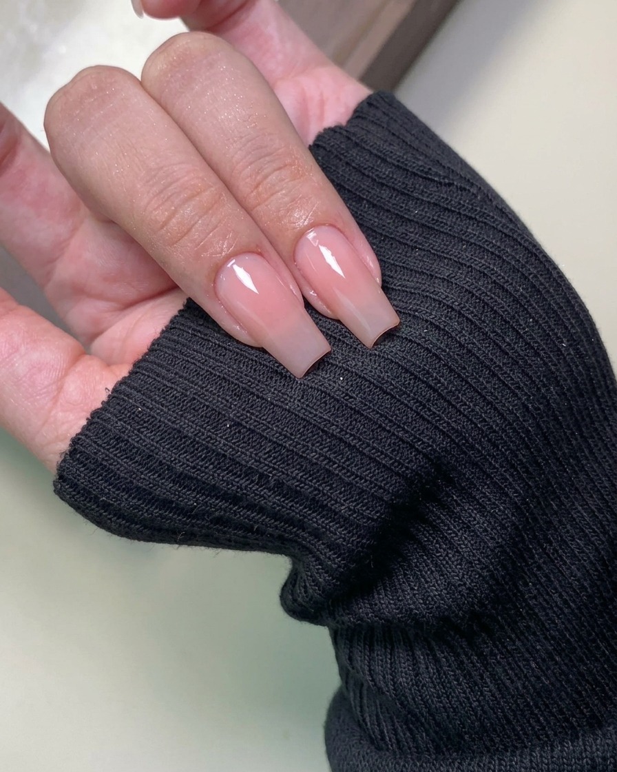 A close-up of a lint-free wipe cleaning the surface of a manicured nail.