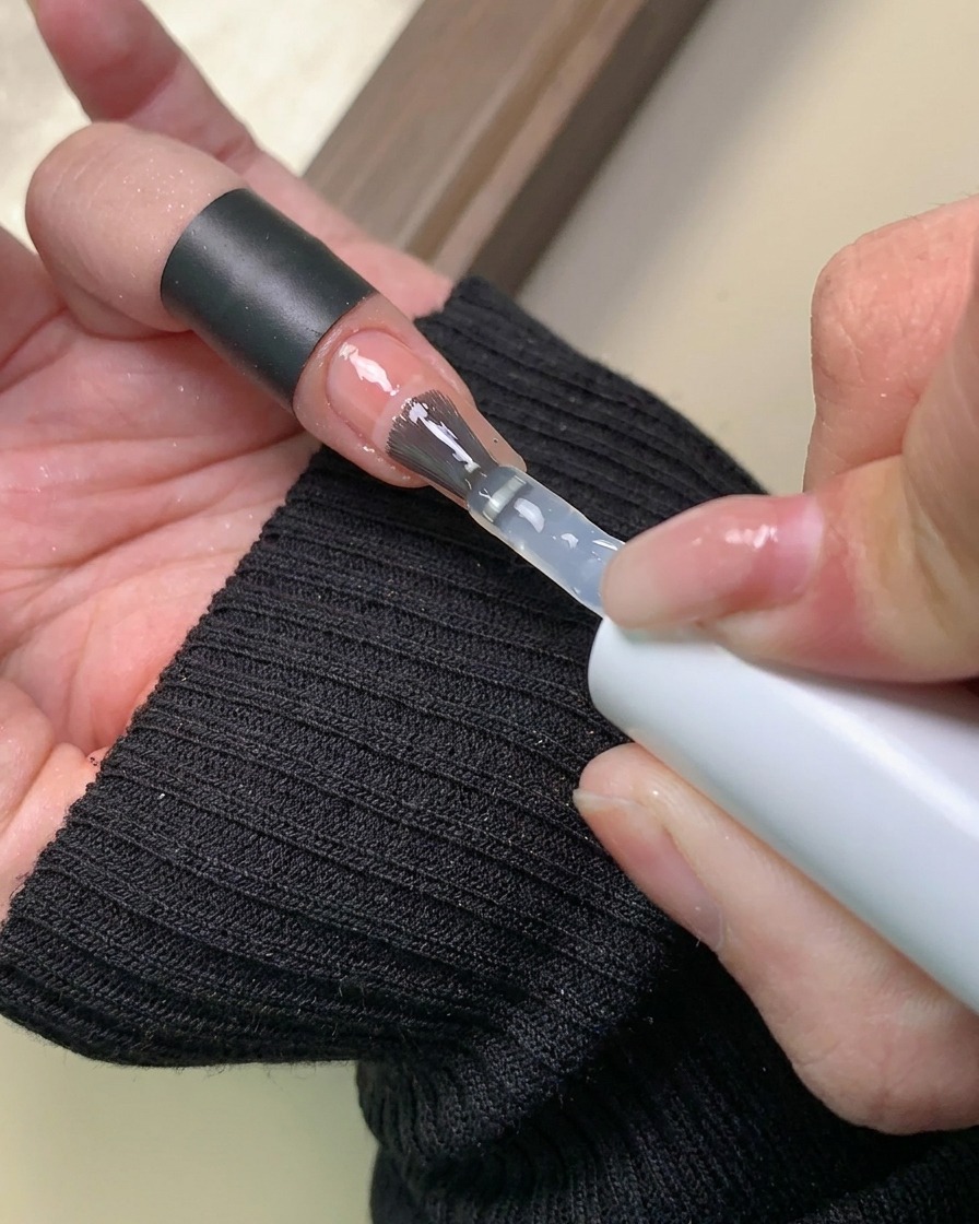 A brush applying a clear layer of base gel over the completed aurora powder gradient design.