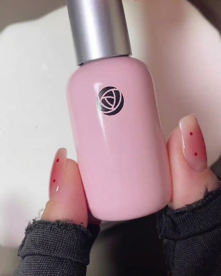 A detail shot of a brush dabbing a small amount of sheer red blush gel onto the center of a matte nail.